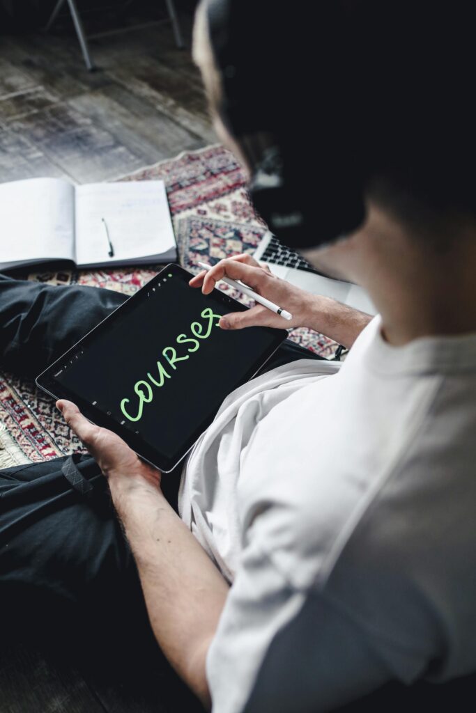 Individual wearing headphones using a digital tablet for online learning. Indoors setting.